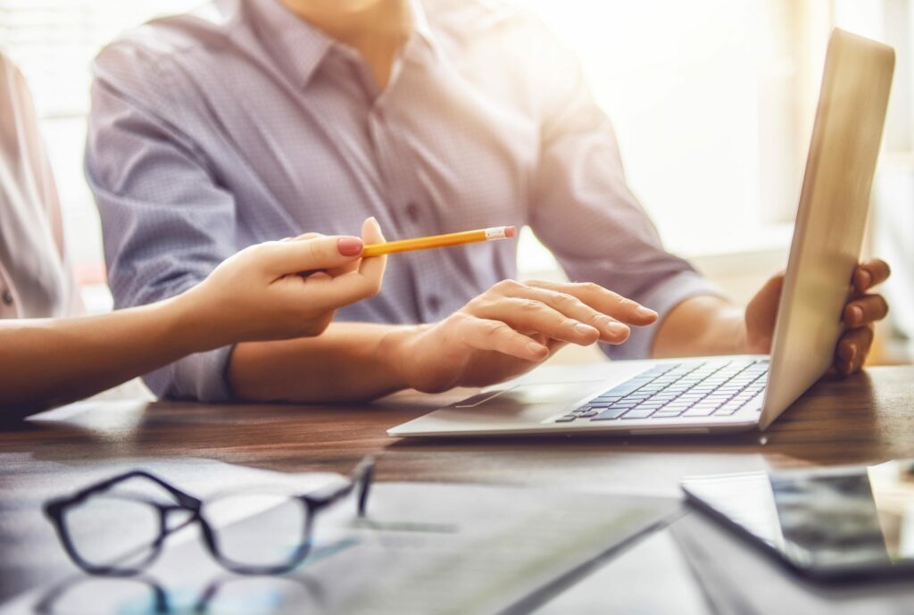 Two people discuss an article on a laptop